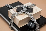 Chain-locked book, phone, and laptop symbolizing digital and intellectual security.