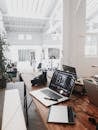 A bright, modern workspace featuring laptops, a camera, and a drawing tablet in an indoor office.
